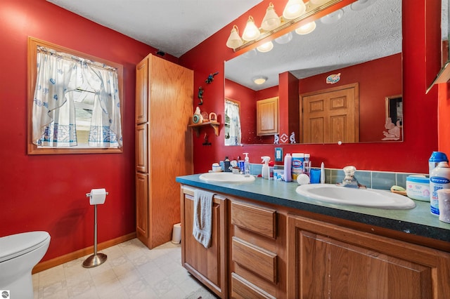 bathroom featuring double vanity, toilet, a sink, and tile patterned floors