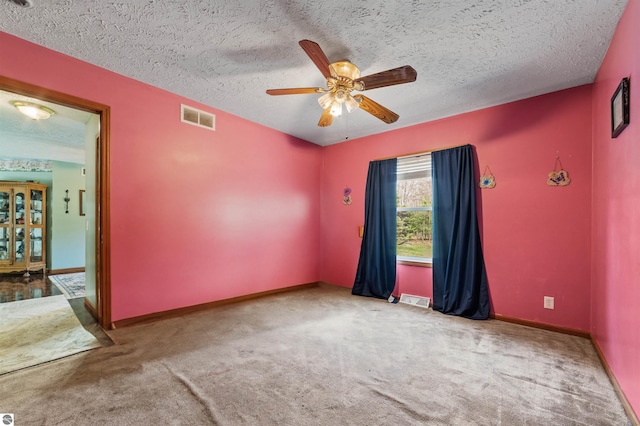 carpeted spare room featuring a ceiling fan, a textured ceiling, visible vents, and baseboards