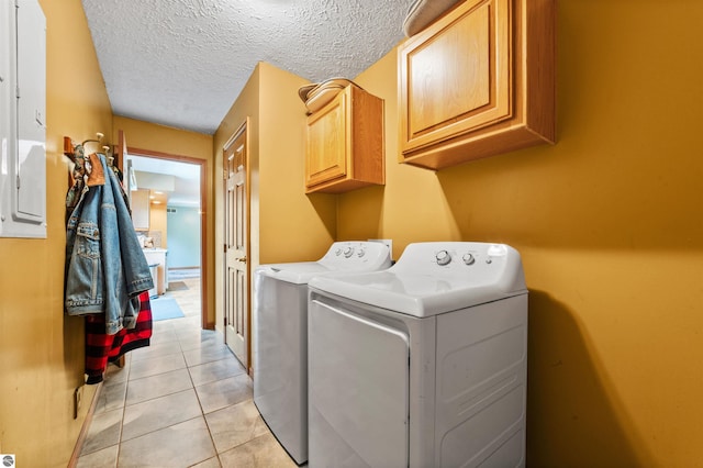 clothes washing area featuring cabinet space, a textured ceiling, washing machine and dryer, and light tile patterned floors