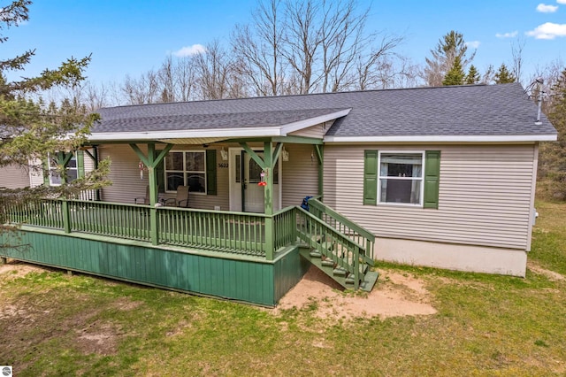 view of front of home featuring a porch, roof with shingles, and a front yard