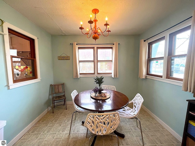 dining room featuring baseboards, a textured ceiling, and a chandelier