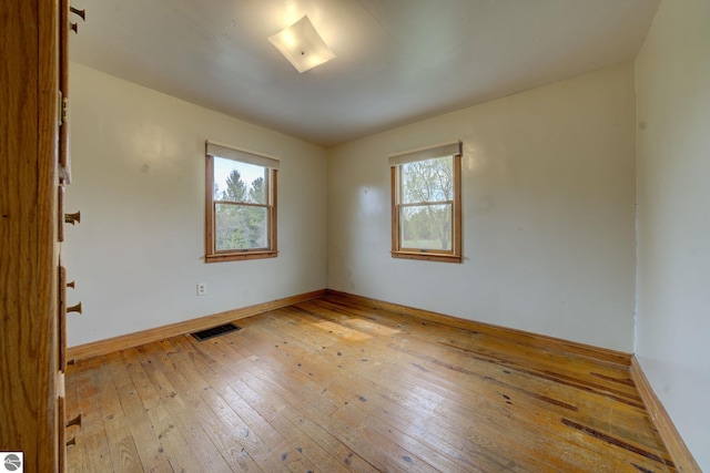 spare room with visible vents, wood-type flooring, plenty of natural light, and baseboards