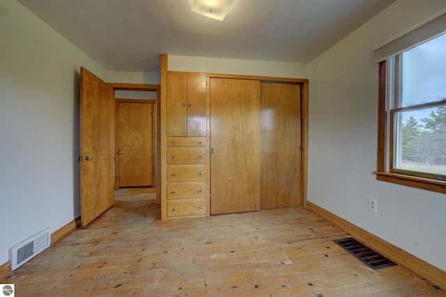 unfurnished bedroom featuring baseboards, visible vents, and light wood finished floors
