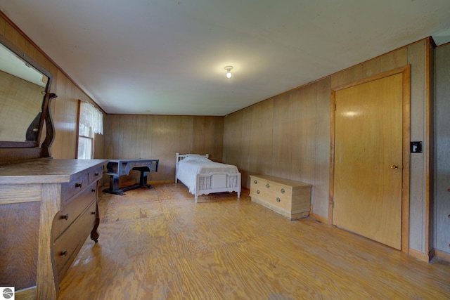 bedroom with wood walls and light wood-style flooring