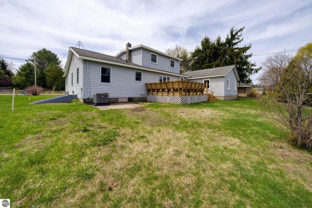 back of property featuring a lawn, central AC unit, a chimney, and a deck