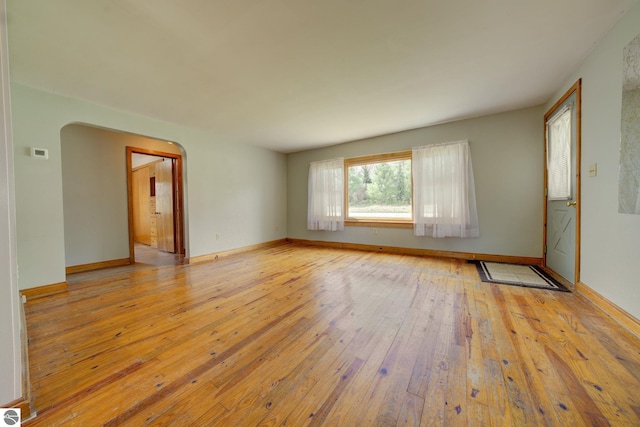 interior space with arched walkways, baseboards, and light wood-style flooring