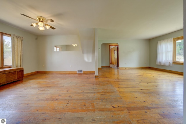 interior space with visible vents, wood-type flooring, baseboards, ceiling fan, and arched walkways