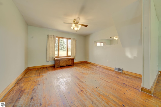 spare room with wood-type flooring, a ceiling fan, baseboards, and visible vents