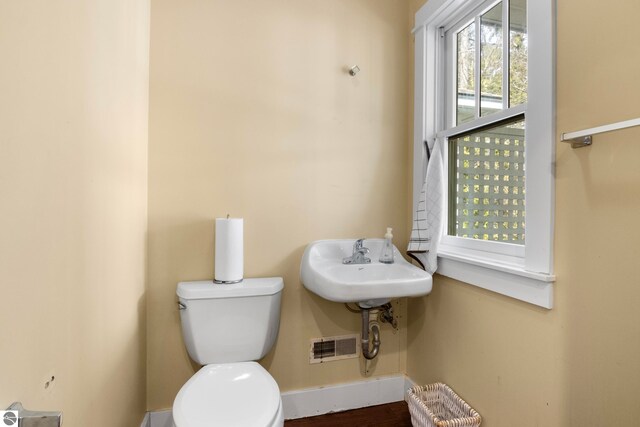 300 S Grand Ave, Leland, MI 49654 - half bathroom featuring baseboards, toilet, wood finished floors, and visible vents