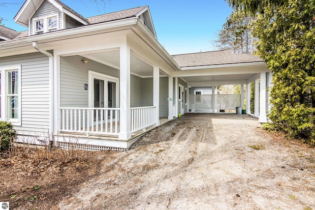 300 S Grand Ave, Leland, MI 49654 - view of side of home featuring covered porch, french doors, roof with shingles, and dirt driveway