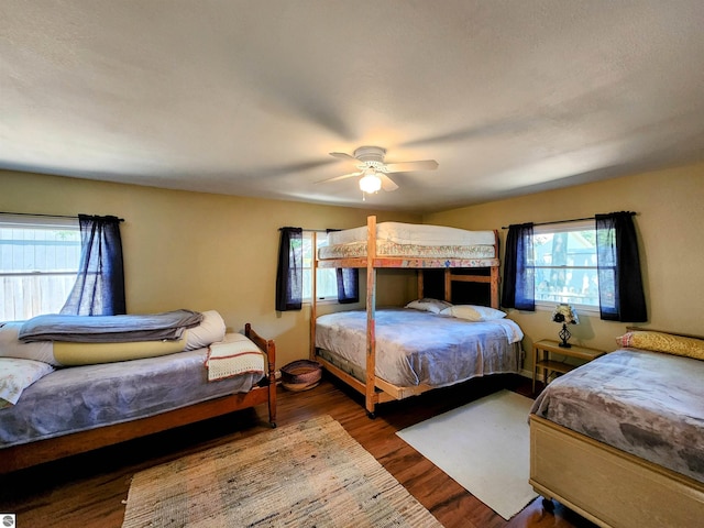 bedroom featuring a ceiling fan, wood finished floors, and multiple windows