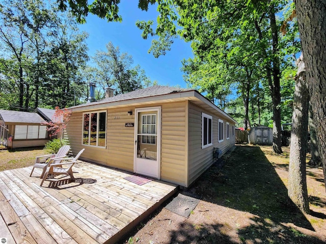 back of property featuring an outbuilding, a deck, and a shed