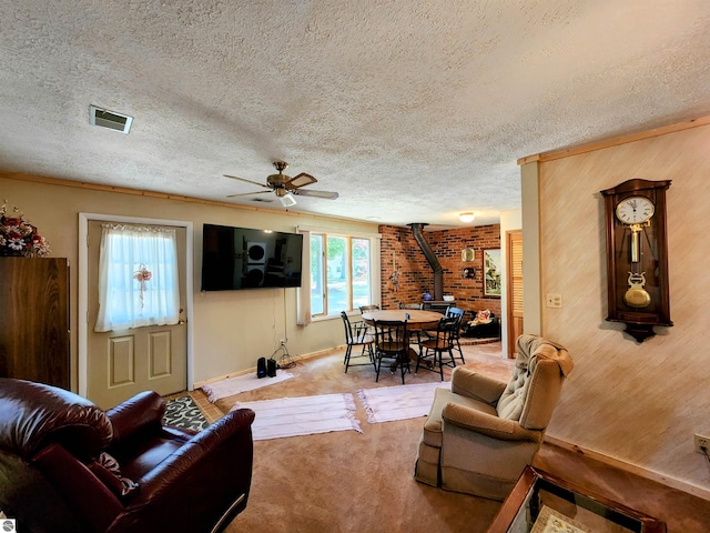living room featuring visible vents, a wood stove, a ceiling fan, and a healthy amount of sunlight