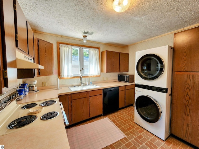 kitchen with stacked washer / drying machine, brown cabinets, a sink, black appliances, and under cabinet range hood