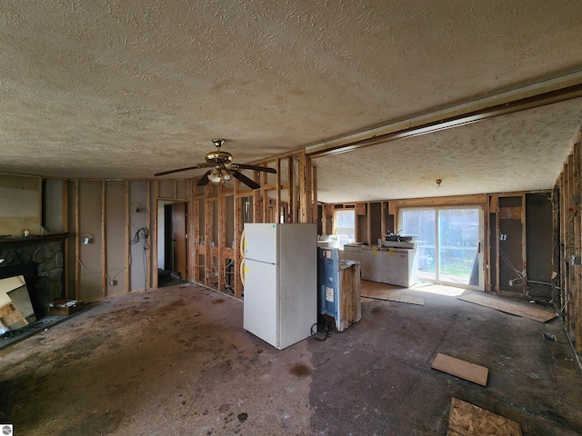 6889 Carpenter Rd, Whittemore, MI 48770 - unfurnished living room featuring a ceiling fan, a textured ceiling, and a fireplace