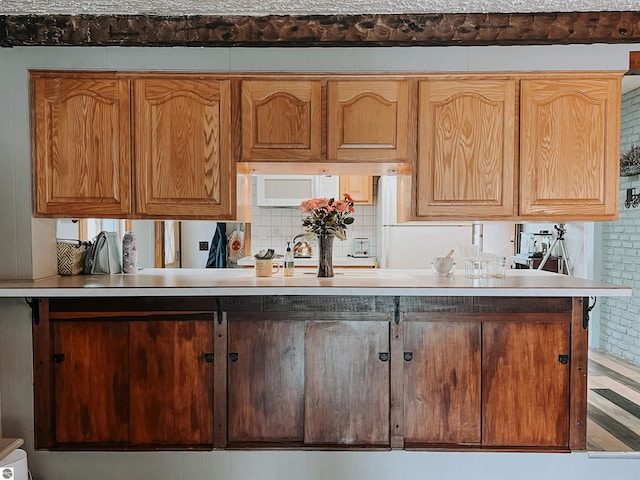 kitchen with light countertops, backsplash, and white microwave