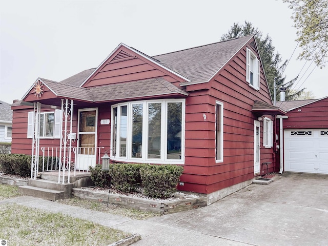view of front facade featuring a shingled roof, an attached garage, and driveway