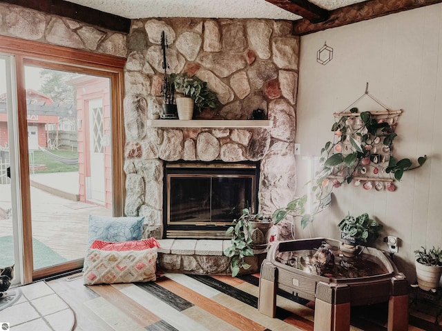 living area featuring a stone fireplace and beam ceiling