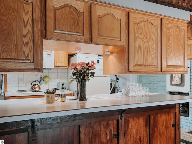 kitchen with white appliances, backsplash, and light countertops