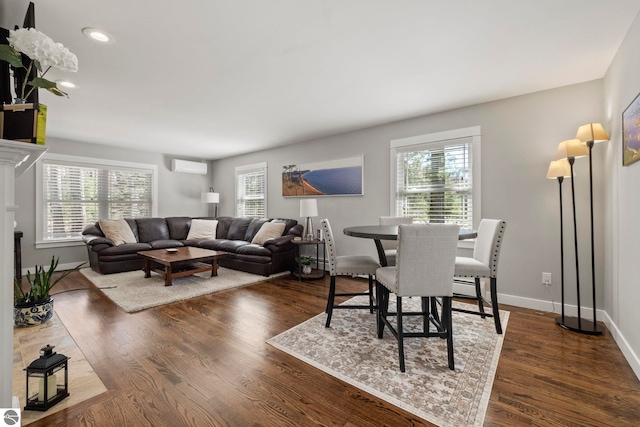 9086 N Tottenham Dr, Traverse City, MI 49685 - living area featuring dark wood-type flooring, baseboards, a wall unit AC, and a healthy amount of sunlight