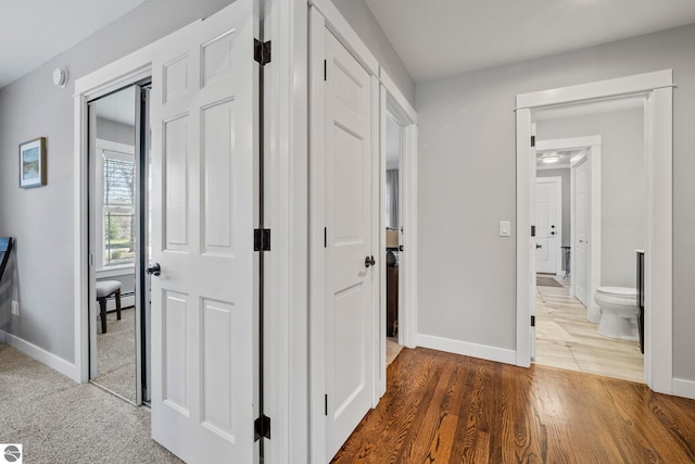 9086 N Tottenham Dr, Traverse City, MI 49685 - hallway featuring baseboards, wood finished floors, and a baseboard radiator