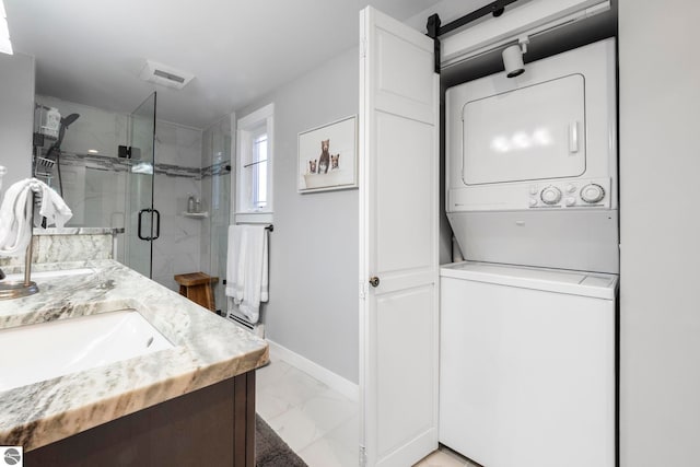 9086 N Tottenham Dr, Traverse City, MI 49685 - washroom featuring laundry area, marble finish floor, baseboards, a sink, and stacked washer / drying machine