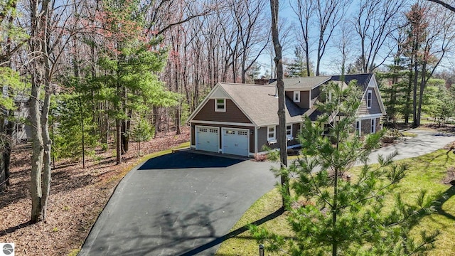 9086 N Tottenham Dr, Traverse City, MI 49685 - view of property exterior with a shingled roof, a chimney, and driveway
