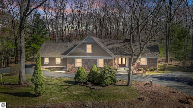 9086 N Tottenham Dr, Traverse City, MI 49685 - view of front of house with brick siding, driveway, a chimney, and a front yard