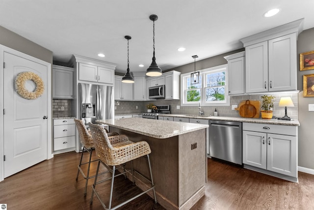 kitchen with a center island, decorative backsplash, dark wood-style flooring, and stainless steel appliances