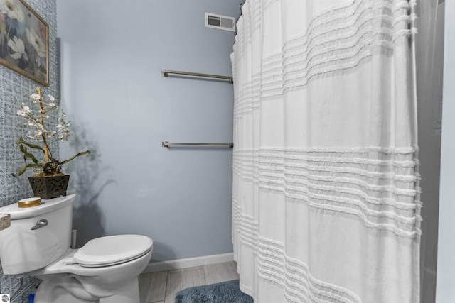 bathroom featuring baseboards, toilet, and visible vents