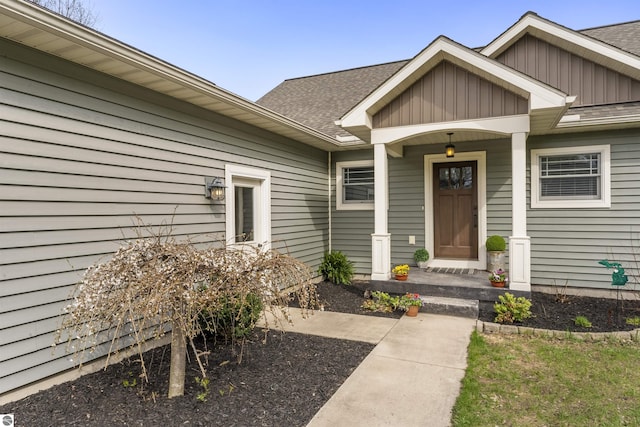 view of exterior entry with board and batten siding and roof with shingles