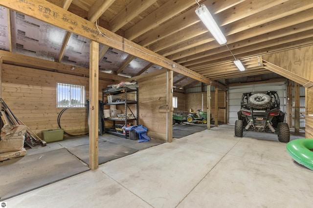interior space with a garage, concrete flooring, and wood walls