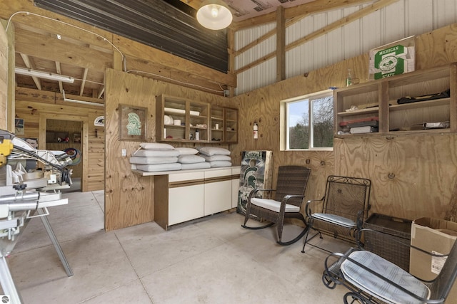 interior space with wood walls, concrete flooring, and vaulted ceiling