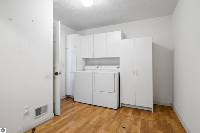 1316 Terra Rd, Traverse City, MI 49686 - laundry room featuring a textured ceiling, baseboards, light wood-type flooring, visible vents, and washer and clothes dryer