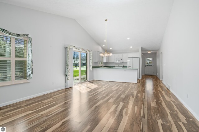 1316 Terra Rd, Traverse City, MI 49686 - unfurnished living room featuring an inviting chandelier, high vaulted ceiling, recessed lighting, baseboards, and wood finished floors