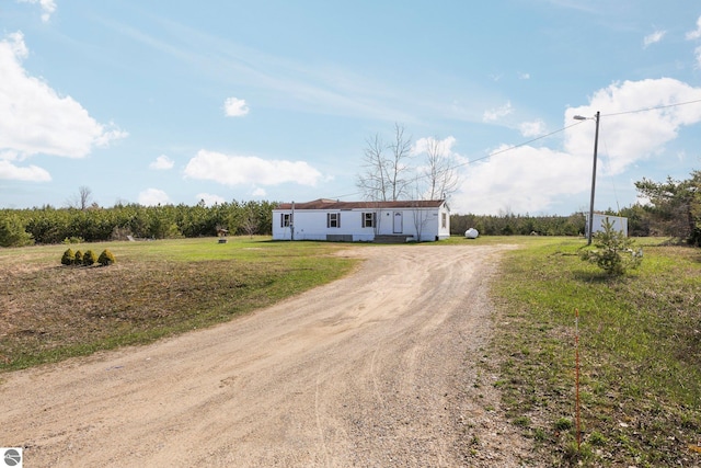 manufactured / mobile home with dirt driveway and a front yard