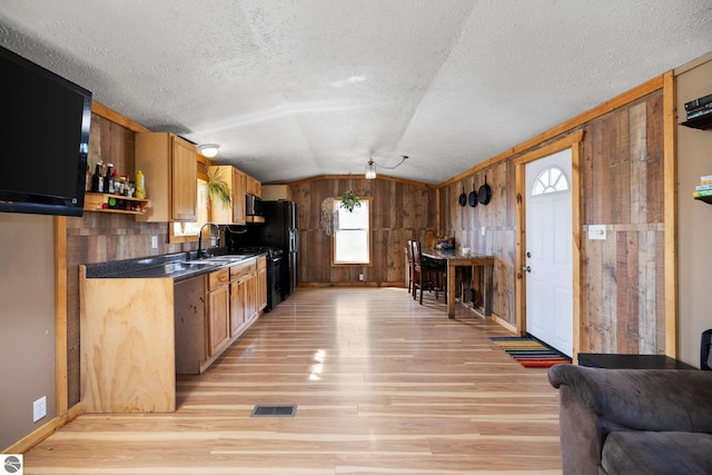 kitchen featuring visible vents, a sink, baseboards, lofted ceiling, and light wood-style floors