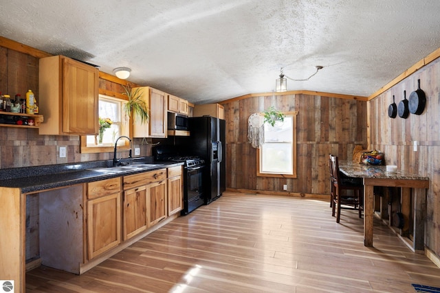 kitchen featuring wood walls, a textured ceiling, black appliances, and vaulted ceiling