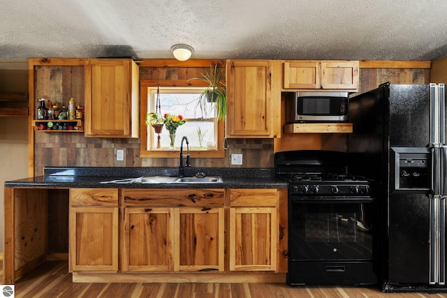 kitchen with a sink, a textured ceiling, black appliances, and dark countertops