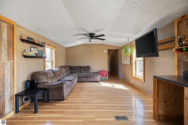 living area featuring visible vents, a ceiling fan, a textured ceiling, and plenty of natural light