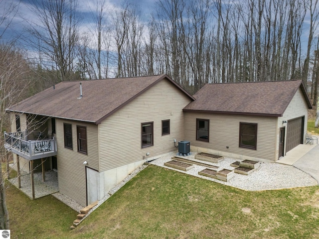 rear view of property with roof with shingles, central air condition unit, a yard, and a deck