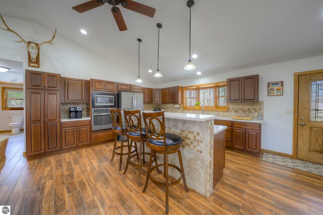 kitchen with light countertops, stainless steel appliances, wood finished floors, and tasteful backsplash
