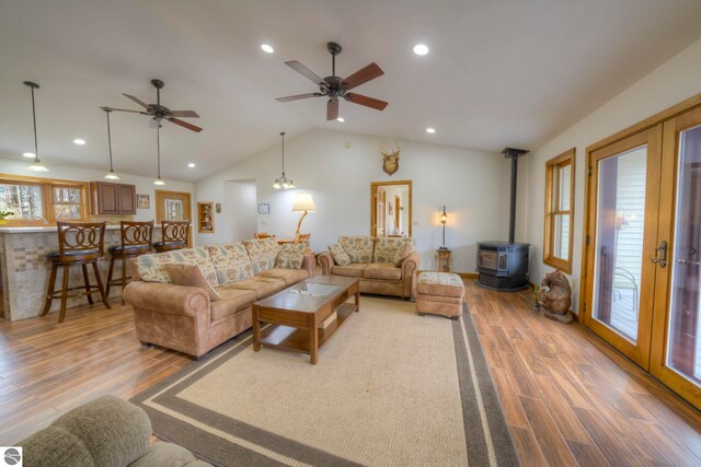 living area featuring a wood stove, lofted ceiling, ceiling fan, recessed lighting, and light wood finished floors