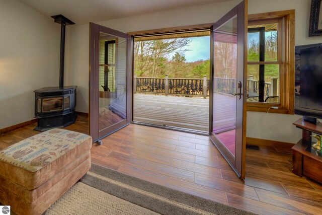 entryway featuring baseboards, a wood stove, and wood finished floors