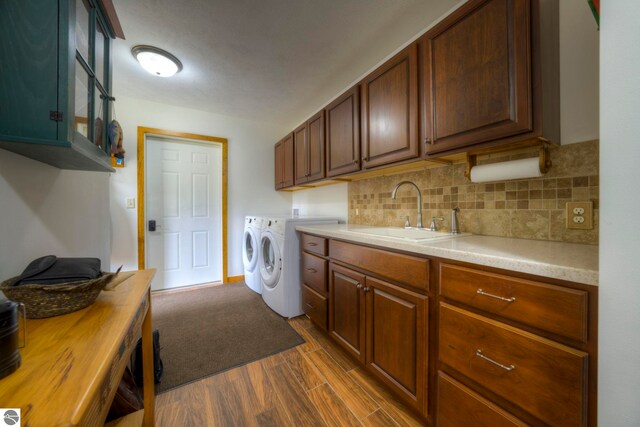 laundry room with a sink, cabinet space, dark wood-style flooring, and washing machine and clothes dryer