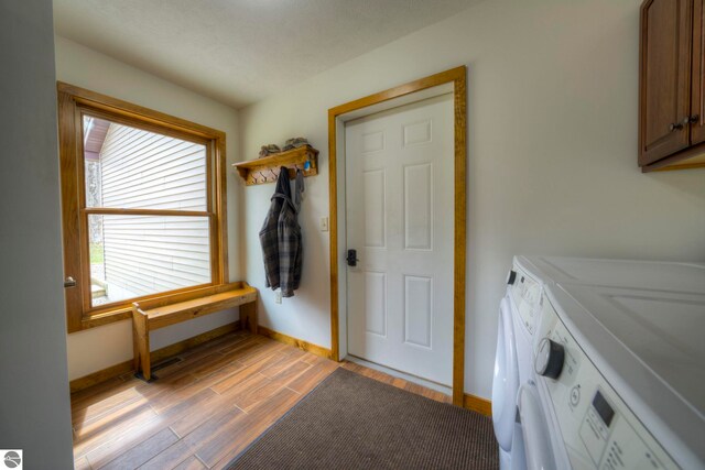 washroom featuring baseboards, light wood-style flooring, cabinet space, and washer and dryer