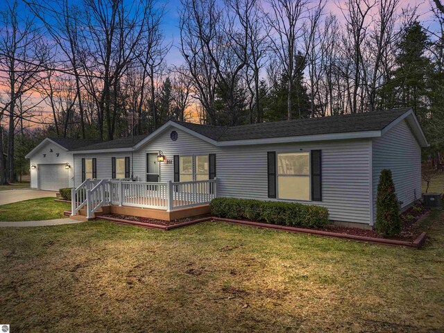 view of front of property featuring a garage, a wooden deck, central AC unit, a yard, and driveway