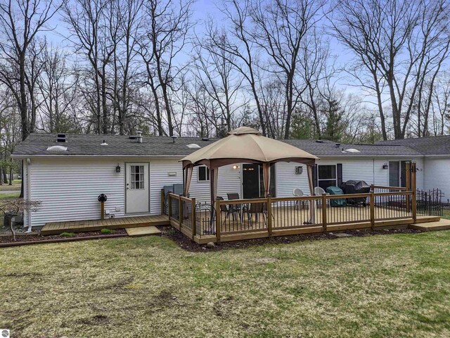 rear view of house with a gazebo, a lawn, and a deck