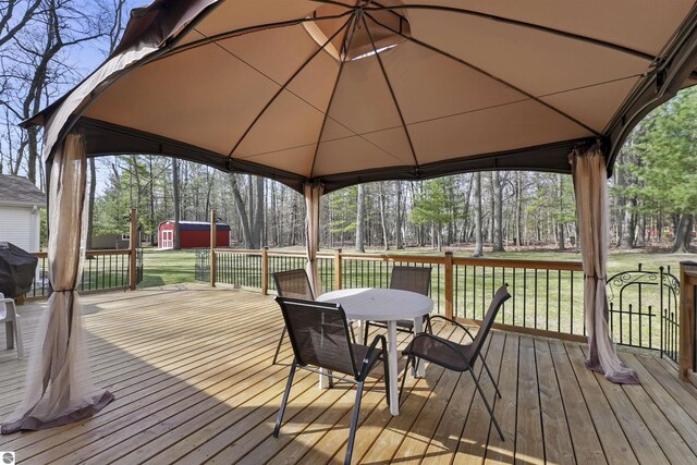 deck with a gazebo, an outdoor structure, a storage unit, a yard, and outdoor dining space