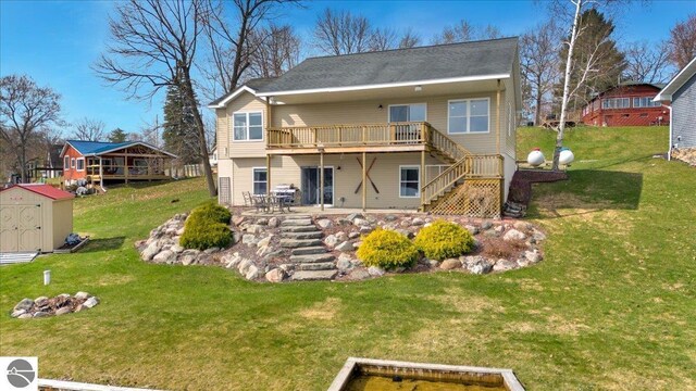 rear view of house with a storage shed, a deck, stairway, an outdoor structure, and a yard